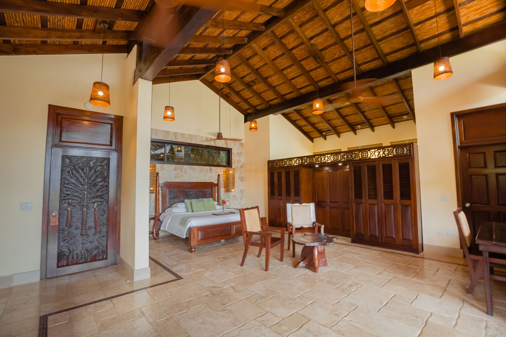 A corner view of the bedroom showing the bed, small dining table and closet as well as the exit door and the bathroom door inside the Mountain View Penthouse at The Rainforest Lodge at Sleeping Giant