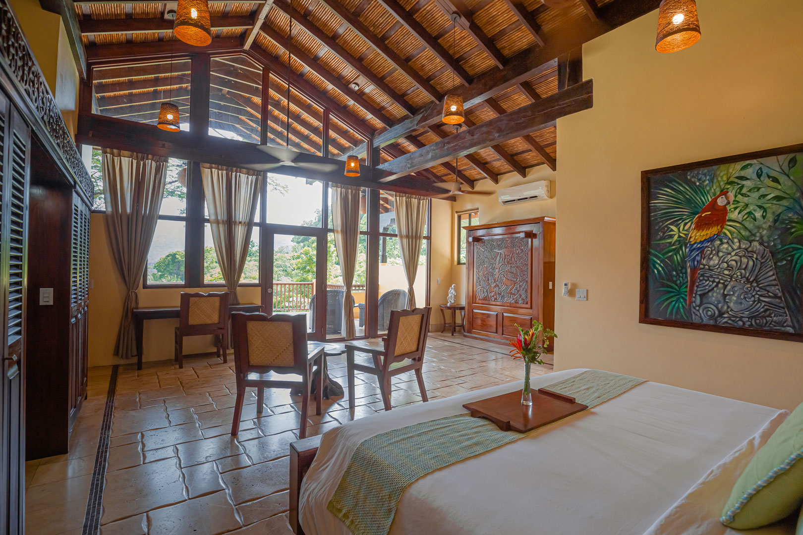 Corner view of the room showing the bed, small dining table and glass doors inside the Mountain View Penthouse at The Rainforest Lodge at Sleeping Giant