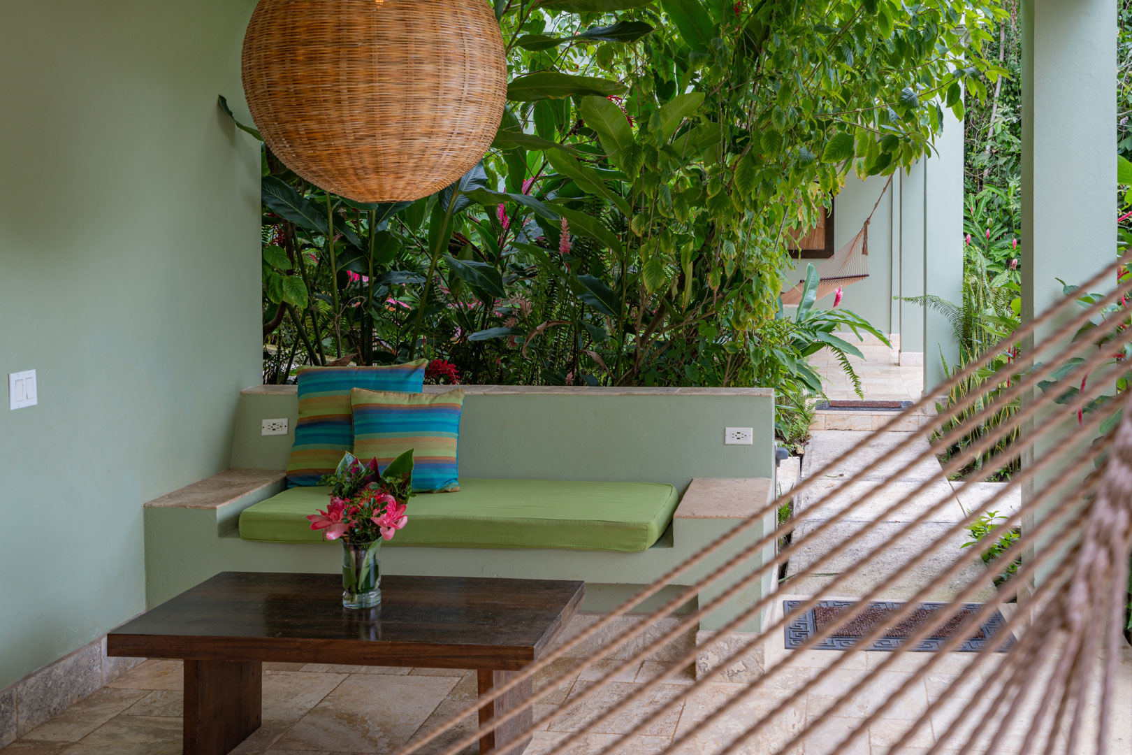 The front porch with a bench and small table outside of the Riverside Room at The Rainforest Lodge at Sleeping Giant