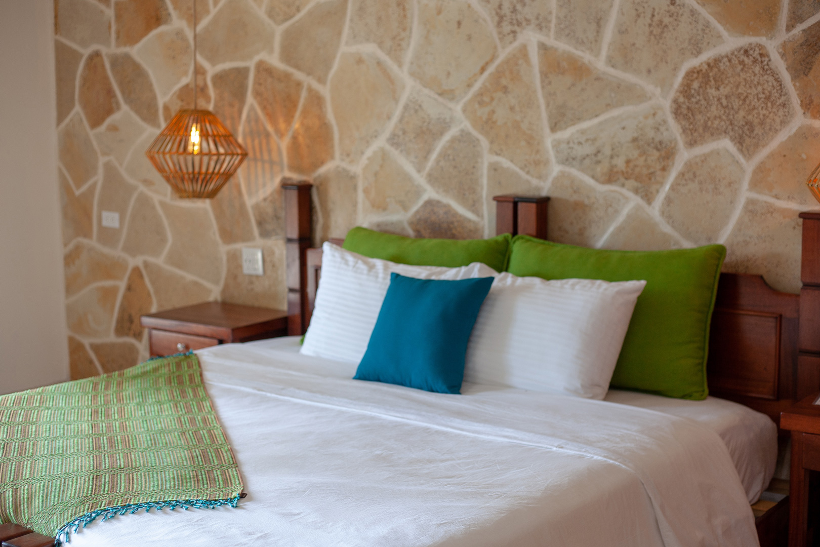 The king sized bed with pillows and linen inside of the Riverside Room at The Rainforest Lodge at Sleeping Giant